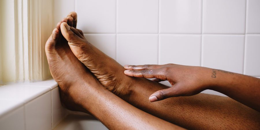 Massaging feet in bathtub.